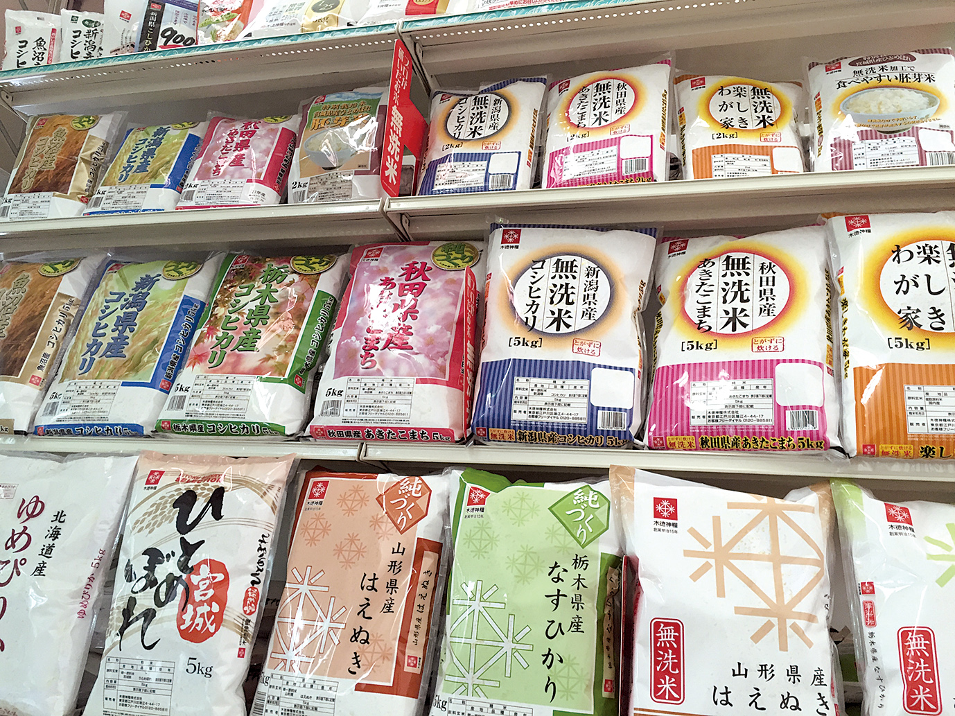 店頭の米売り場。色とりどりのパッケージで、北海道、宮城、秋田、山形、栃木、新潟など各地の銘柄米が並んでいる。